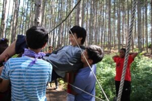 Here are children learning teamwork, leadership, and problem solving skills while using the low ropes course at SMC.